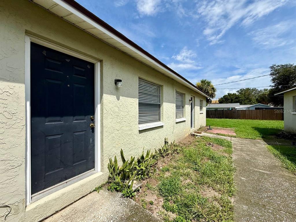 A side view of a light-colored stucco house with a dark door and windows — 3107 W MARCUM STREET UNIT A, TAMPA, FL