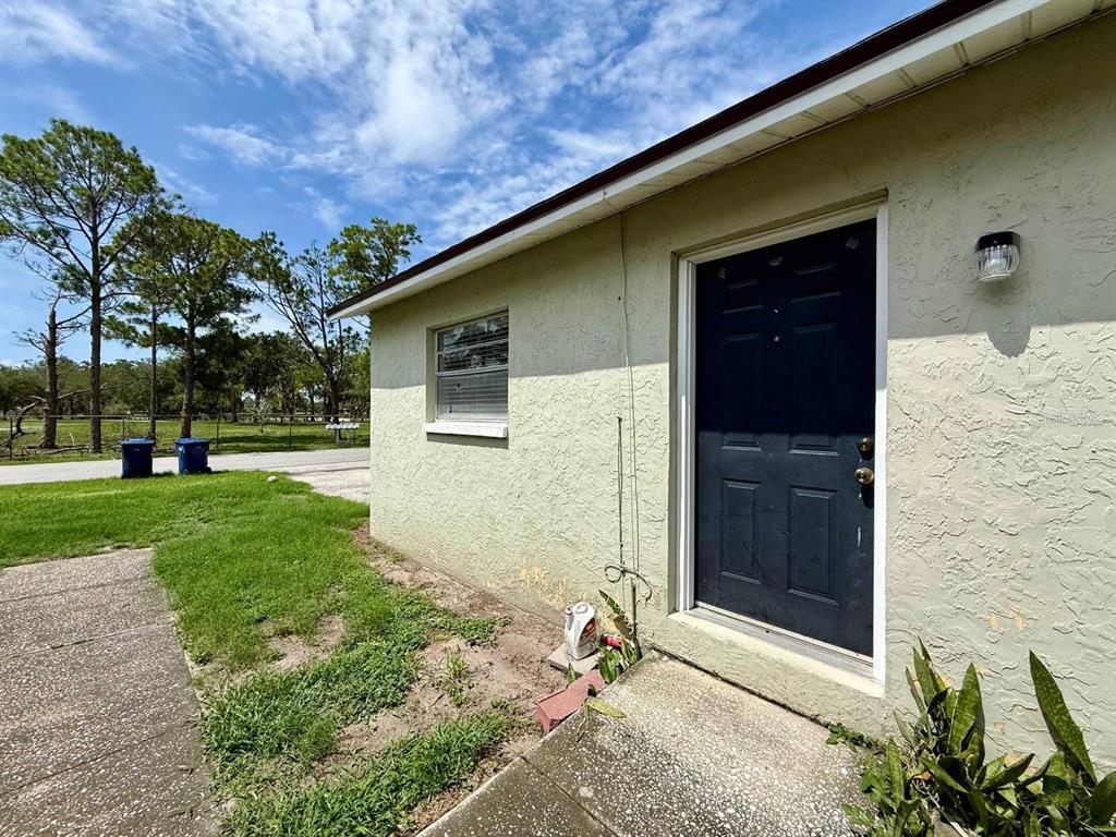 Exterior view of a light green stucco house with a dark blue door and window — 3107 W MARCUM STREET UNIT A, TAMPA, FL