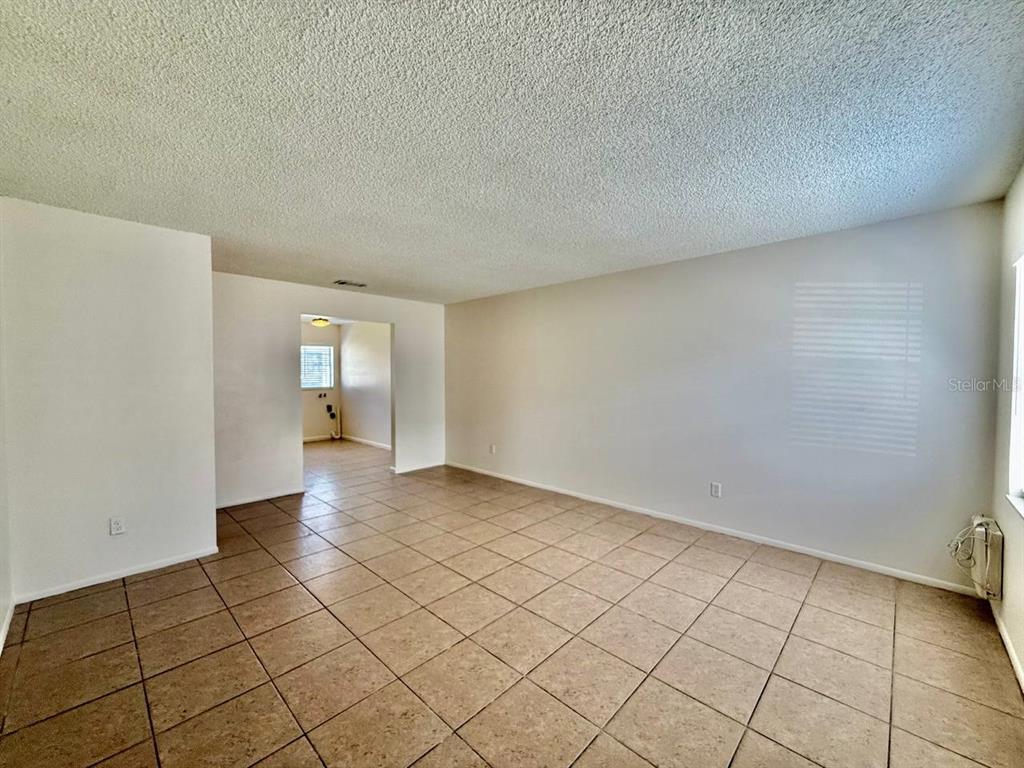 An empty room with beige tile flooring, white walls, and a textured ceiling — 3107 W MARCUM STREET UNIT A, TAMPA, FL