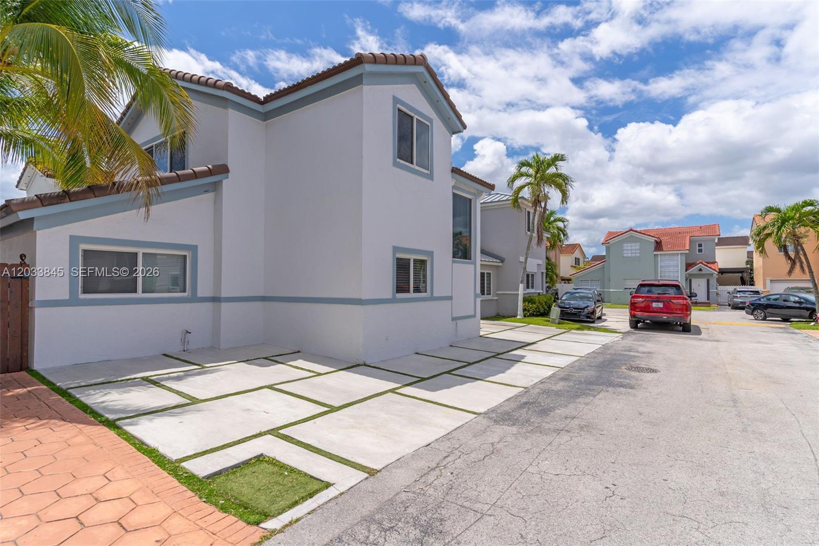 A two-story house with a paved driveway and palm trees under a cloudy sky — 979 NW 126th Path, Miami FL 33182, MIAMI, FL