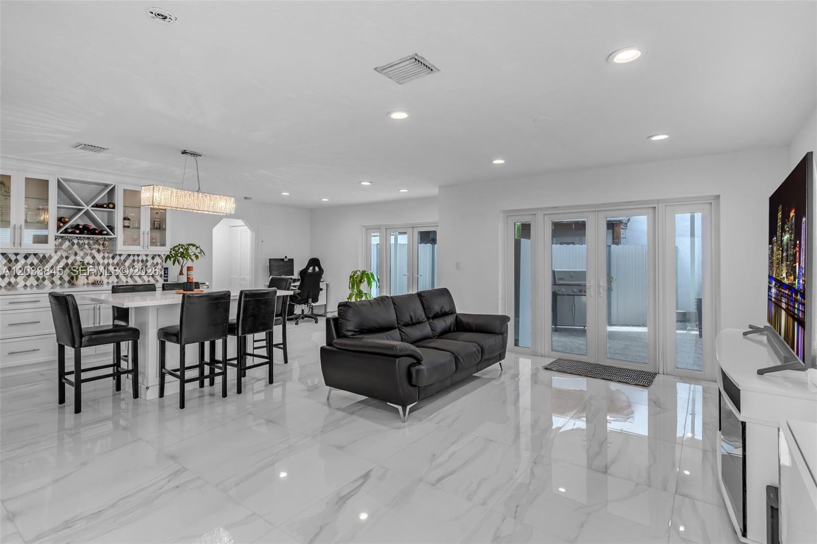 A bright, open-concept living and dining area features white marble floors and black furniture — 979 NW 126th Path, Miami FL 33182, MIAMI, FL