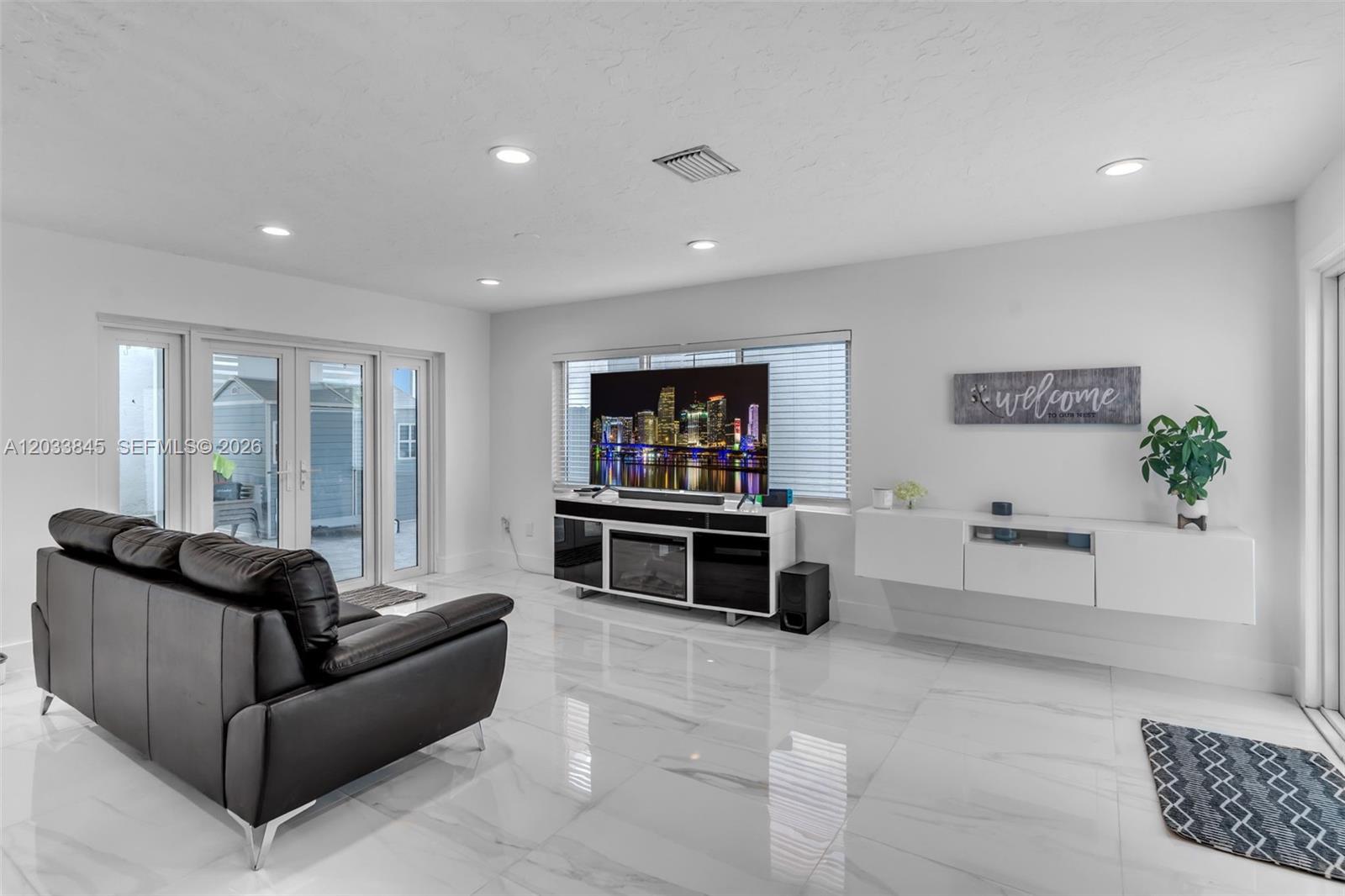 A living room features white marble floors, a black leather sofa, and a wall-mounted television — 979 NW 126th Path, Miami FL 33182, MIAMI, FL