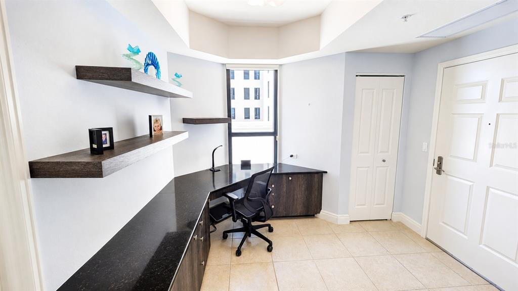 A home office features a corner desk with a black countertop and floating wall shelves — 50 CENTRAL AVENUE UNIT 11A, SARASOTA, FL