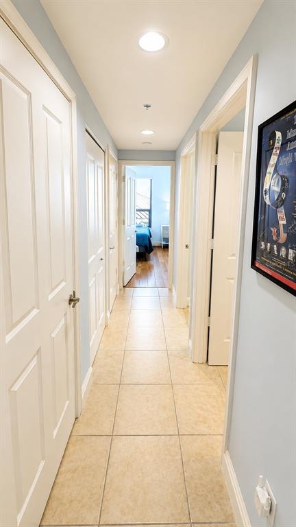 A hallway with light-colored tile flooring leads to a bedroom with hardwood floors — 50 CENTRAL AVENUE UNIT 11A, SARASOTA, FL