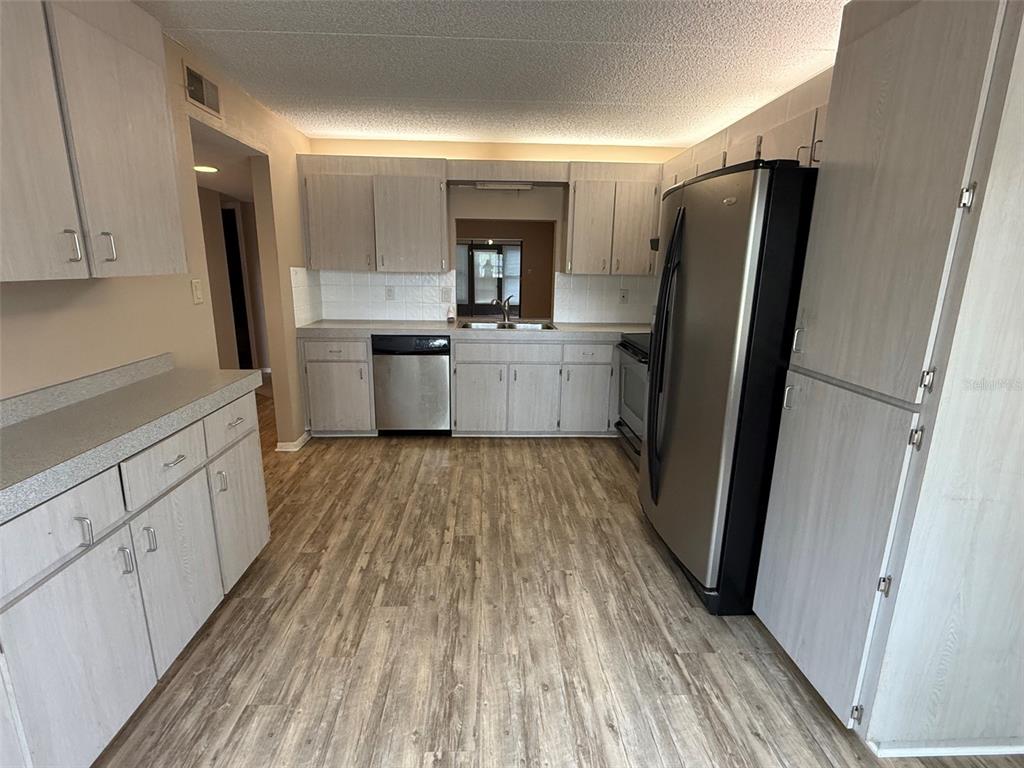 A kitchen features light wood-grain cabinets, stainless steel appliances, and wood-look flooring — 8621 SHADBLOW COURT UNIT 4, PORT RICHEY, FL