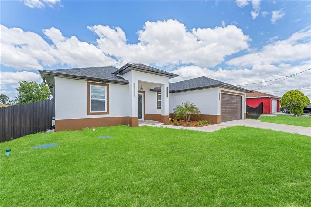A single-story house with white stucco walls, brown trim, and a dark shingled roof — 2914 23RD STREET SW, LEHIGH ACRES, FL