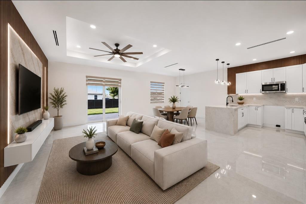 An open-concept living room and kitchen with white cabinetry, a large sofa, and tile flooring — 2914 23RD STREET SW, LEHIGH ACRES, FL