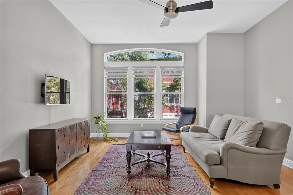 A living room features a grey sofa, a wooden coffee table, and a large arched window — 125 NE 4TH STREET UNIT 38, GAINESVILLE, FL