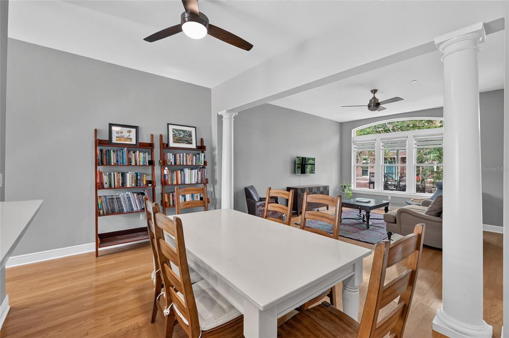 A dining area with a white table and wooden chairs opens into a living room — 125 NE 4TH STREET UNIT 38, GAINESVILLE, FL