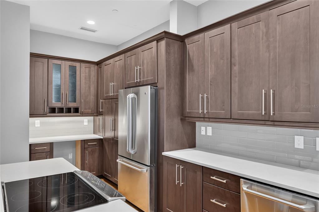 A kitchen features dark wood cabinets, stainless steel appliances, and white countertops with subway tile — 125 NE 4TH STREET UNIT 38, GAINESVILLE, FL