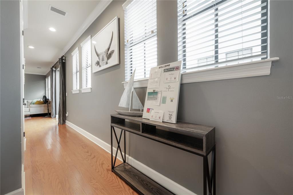 A hallway with hardwood floors, a console table, and a wall-mounted information board — 111 S PACKWOOD AVENUE UNIT C, TAMPA, FL