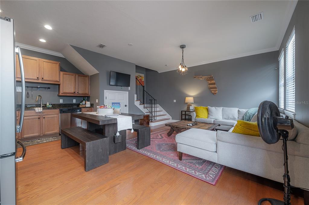An open-concept living area features a kitchen, dining table, and sectional sofa on hardwood floors — 111 S PACKWOOD AVENUE UNIT C, TAMPA, FL