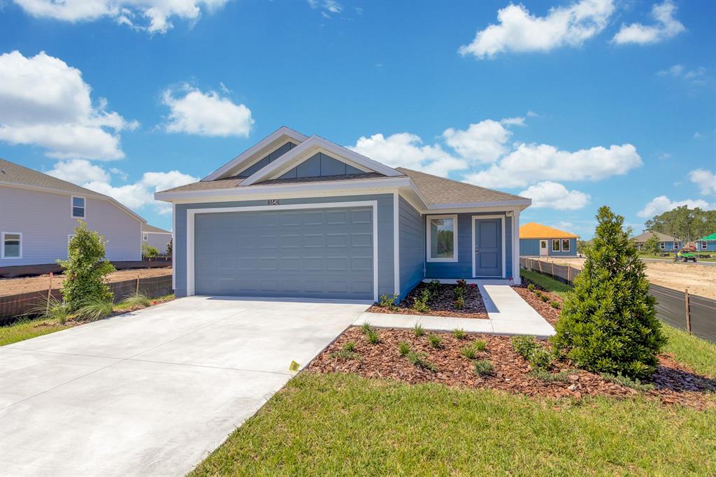 A blue single-story house with a two-car garage and a concrete driveway under a sky — 5540 SAPOTE COURT, KISSIMMEE, FL