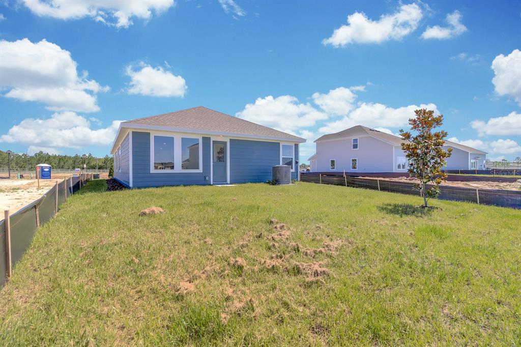 The rear exterior of a blue single-story house features a grassy yard and silt fencing — 5540 SAPOTE COURT, KISSIMMEE, FL