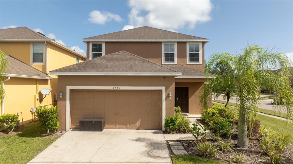 A two-story brown house with a two-car garage and a palm tree in the yard — 2625 SANTOSH COVE, KISSIMMEE, FL