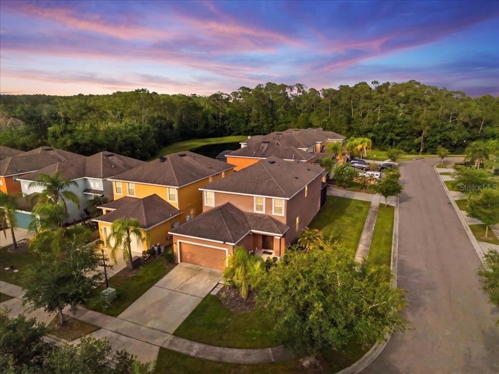 An aerial view shows a suburban neighborhood with two-story houses and a nearby pond — 2625 SANTOSH COVE, KISSIMMEE, FL