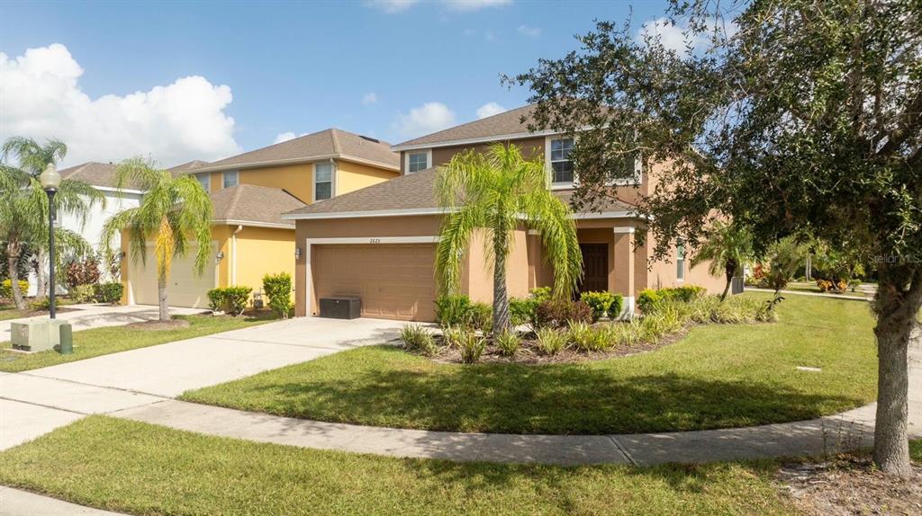 A two-story tan house with a two-car garage and palm trees in the front yard — 2625 SANTOSH COVE, KISSIMMEE, FL
