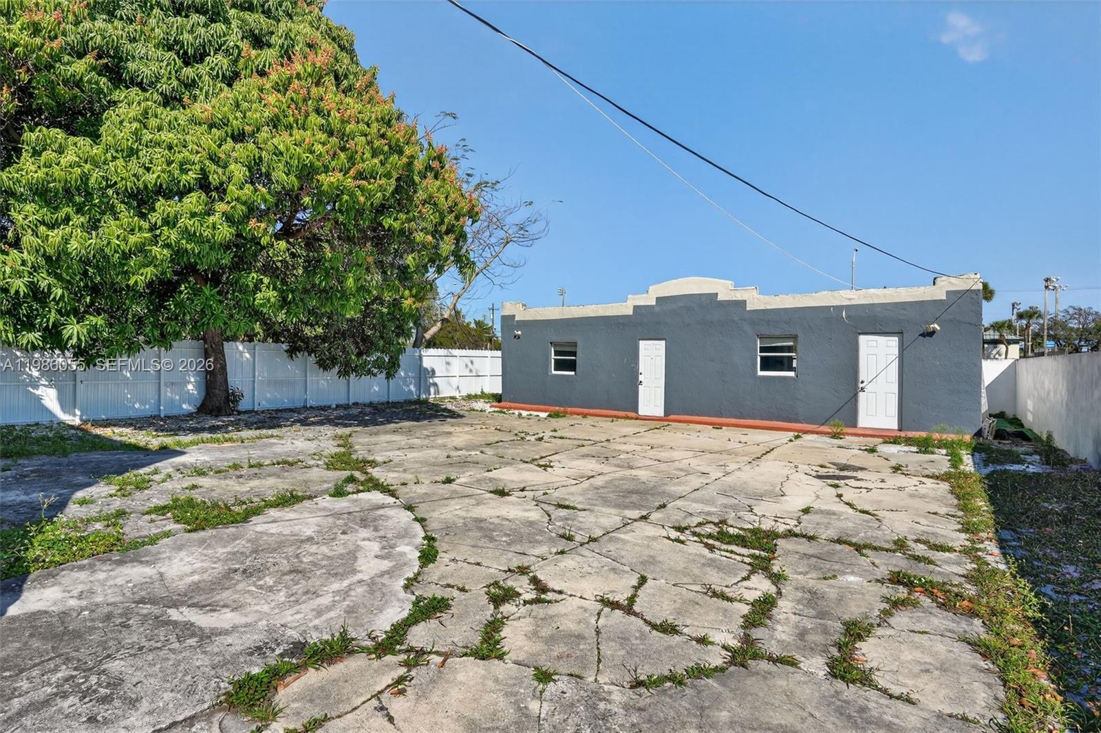 A gray, flat-roofed building sits behind a large, cracked concrete lot with a tree — 767 NW 35th St, Miami FL 33127, MIAMI, FL