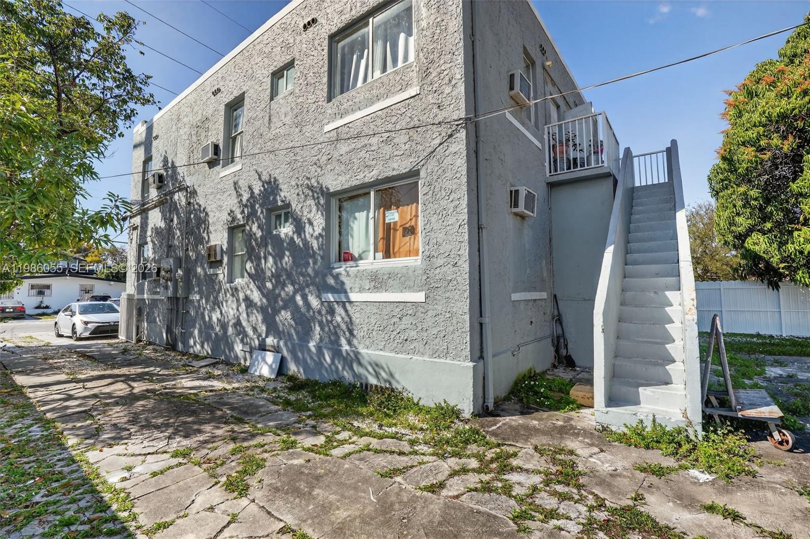 A two-story gray stucco apartment building features an exterior staircase leading to the upper level — 767 NW 35th St, Miami FL 33127, MIAMI, FL