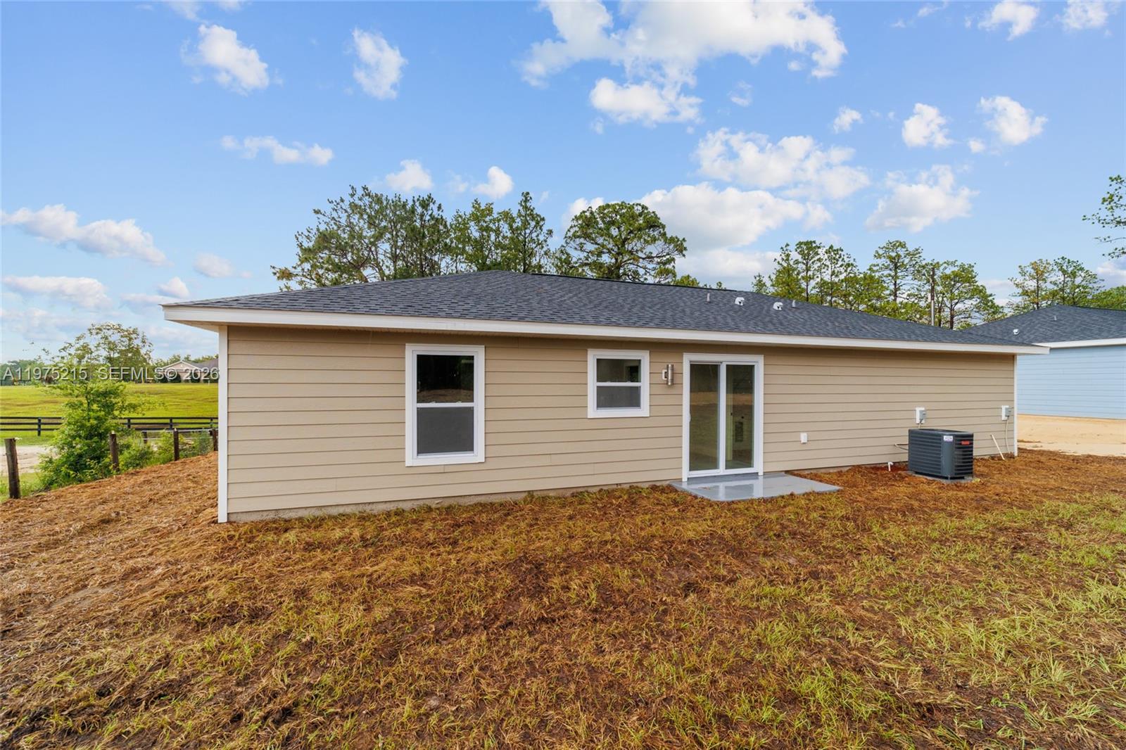The exterior of a tan, single-story house features a sliding glass door and two windows — 15594 SW 38th Place, Ocala FL 33481, OCALA, FL