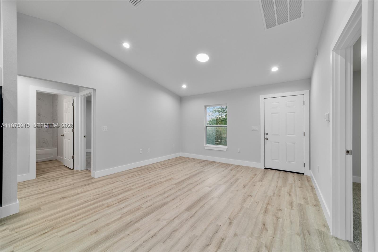 This room features light wood-look flooring, white walls, a vaulted ceiling, and a white door — 15594 SW 38th Place, Ocala FL 33481, OCALA, FL