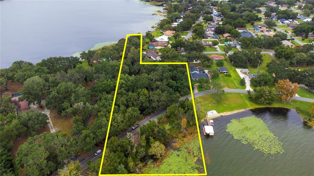 An aerial view shows a wooded lot outlined in yellow bordering a lake — 2060 LAKE ARIANA BOULEVARD, AUBURNDALE, FL