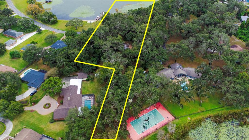An aerial view shows a wooded lot outlined in yellow between two residential properties — 2060 LAKE ARIANA BOULEVARD, AUBURNDALE, FL