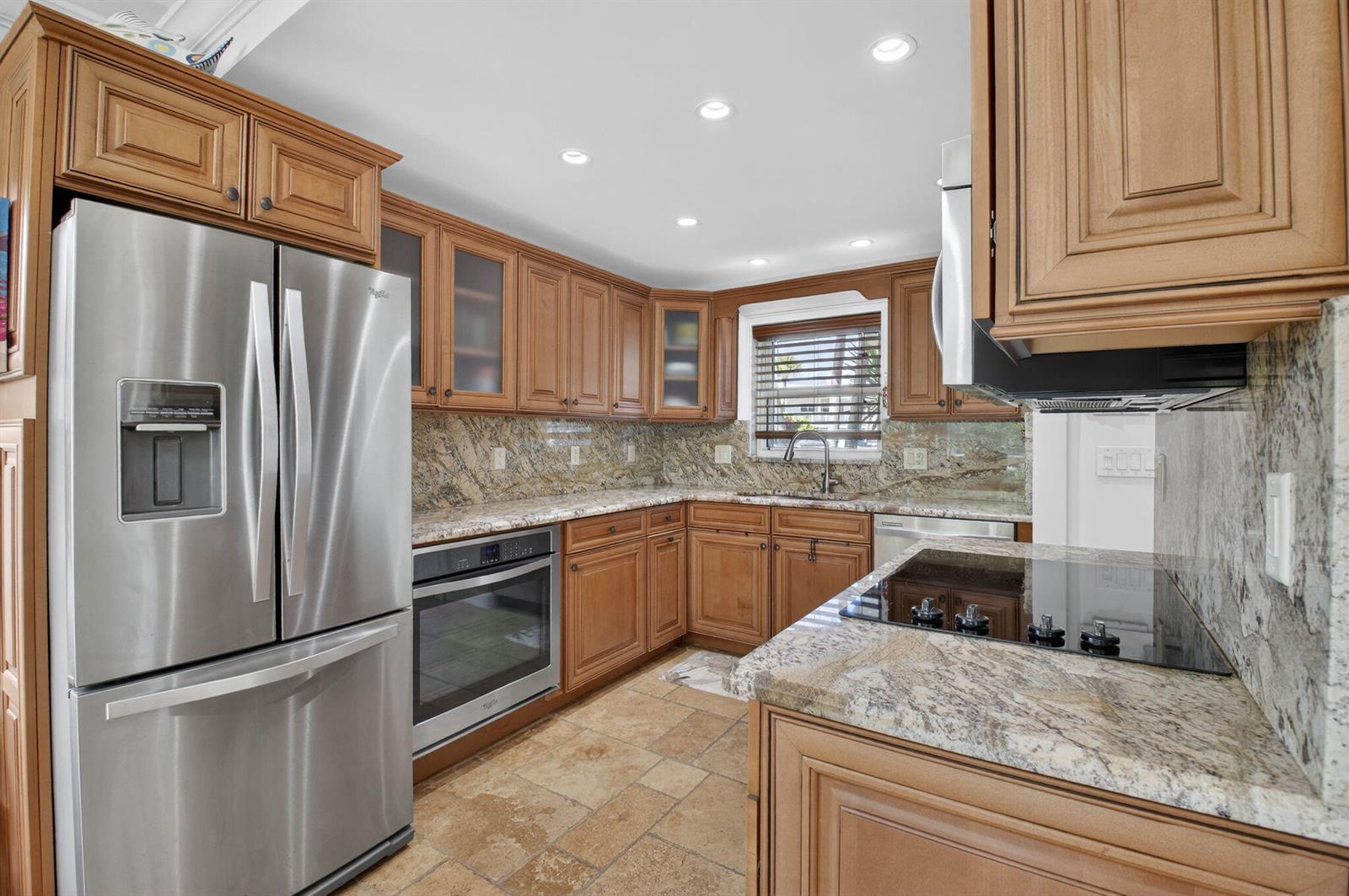 A kitchen features wood cabinets, granite countertops, stainless steel appliances, and tile flooring — 711 NE Harbour Terrace # 3120, Boca Raton FL 33431, BOCA RATON, FL