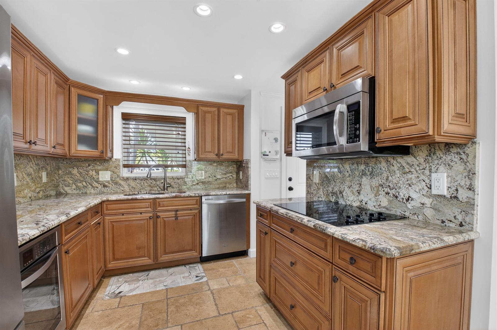 A kitchen features wood cabinets, granite countertops, stainless steel appliances, and tile flooring — 711 NE Harbour Terrace # 3120, Boca Raton FL 33431, BOCA RATON, FL