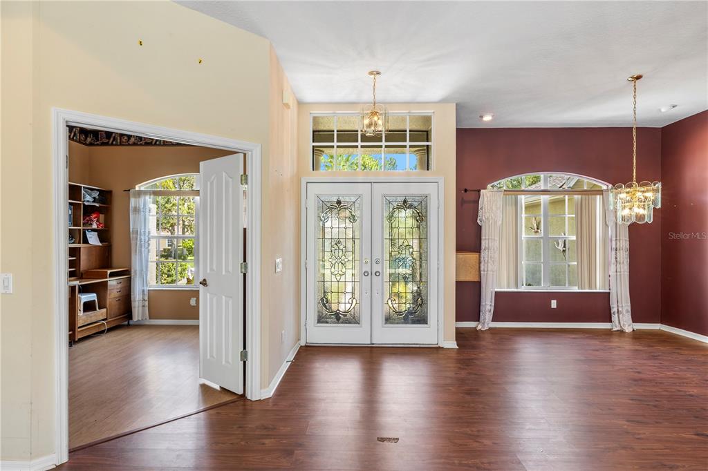 An entryway features double glass-paneled doors, wood-look flooring, and a room with a desk — 5334 LEGEND HILLS LANE, SPRING HILL, FL