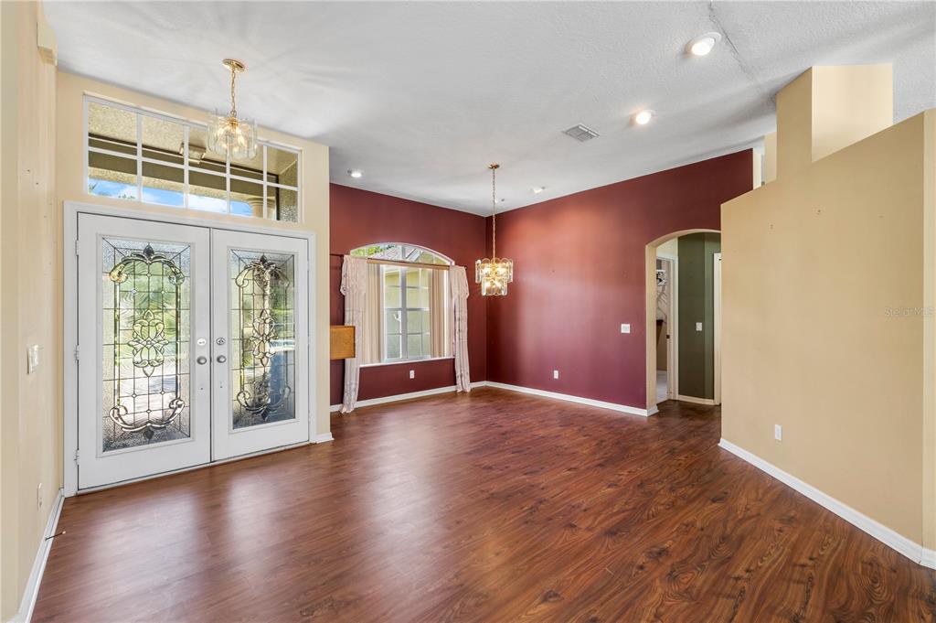 A spacious foyer and dining area features dark wood flooring, red walls, and double doors — 5334 LEGEND HILLS LANE, SPRING HILL, FL