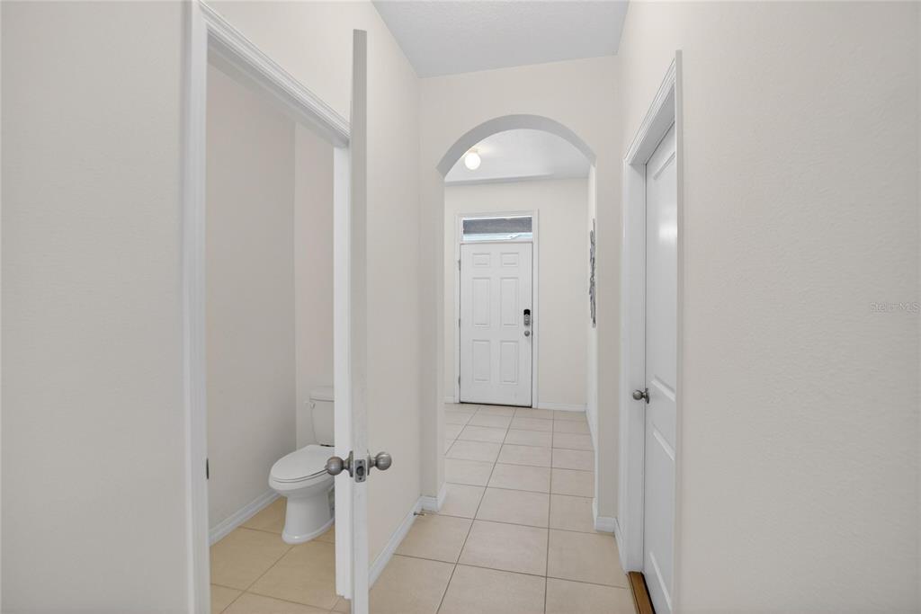 A hallway with tile flooring leads to a front door under an arched entryway — 8850 INDIGO TRAIL LOOP, RIVERVIEW, FL