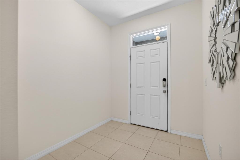 An entryway with light-colored tile flooring, beige walls, and a white front door — 8850 INDIGO TRAIL LOOP, RIVERVIEW, FL