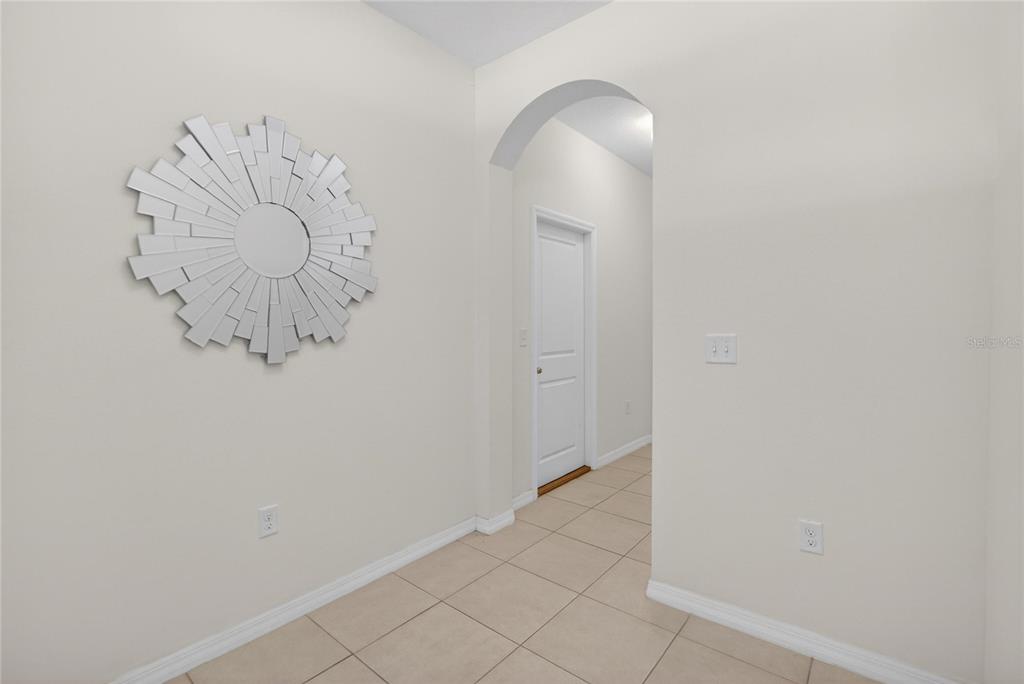 A tiled hallway features a sunburst mirror on the wall and an arched entryway — 8850 INDIGO TRAIL LOOP, RIVERVIEW, FL