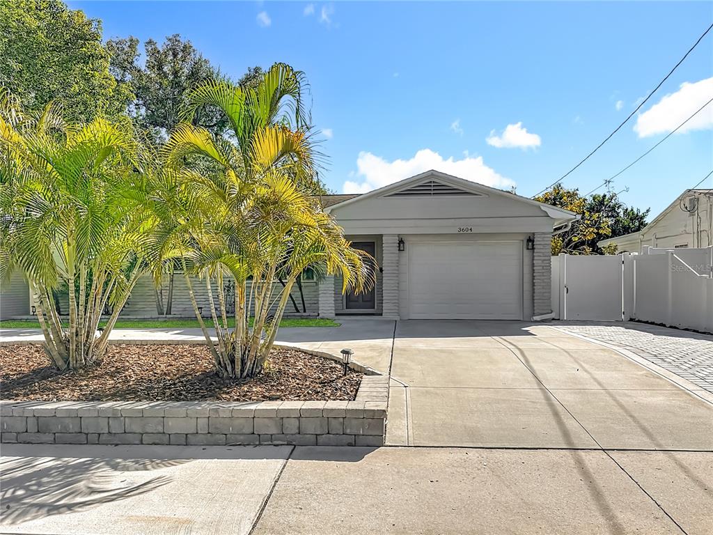 A single-story house with a white garage, concrete driveway, and palm trees in the front yard — 3604 W BAY TO BAY BOULEVARD, TAMPA, FL