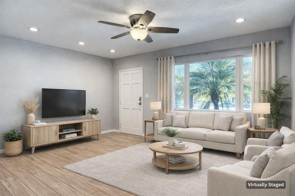 A virtually staged living room with light wood flooring, a ceiling fan, and a large window — 3604 W BAY TO BAY BOULEVARD, TAMPA, FL