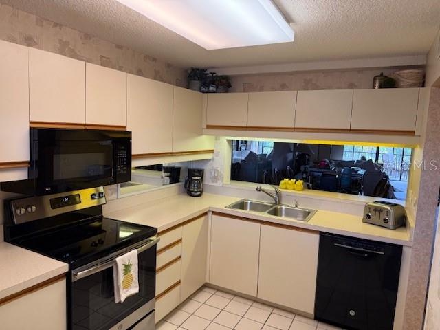 A kitchen features white cabinets, black appliances, a double sink, and a tiled floor — 5525 ASHTON LAKE DRIVE UNIT 5525, SARASOTA, FL