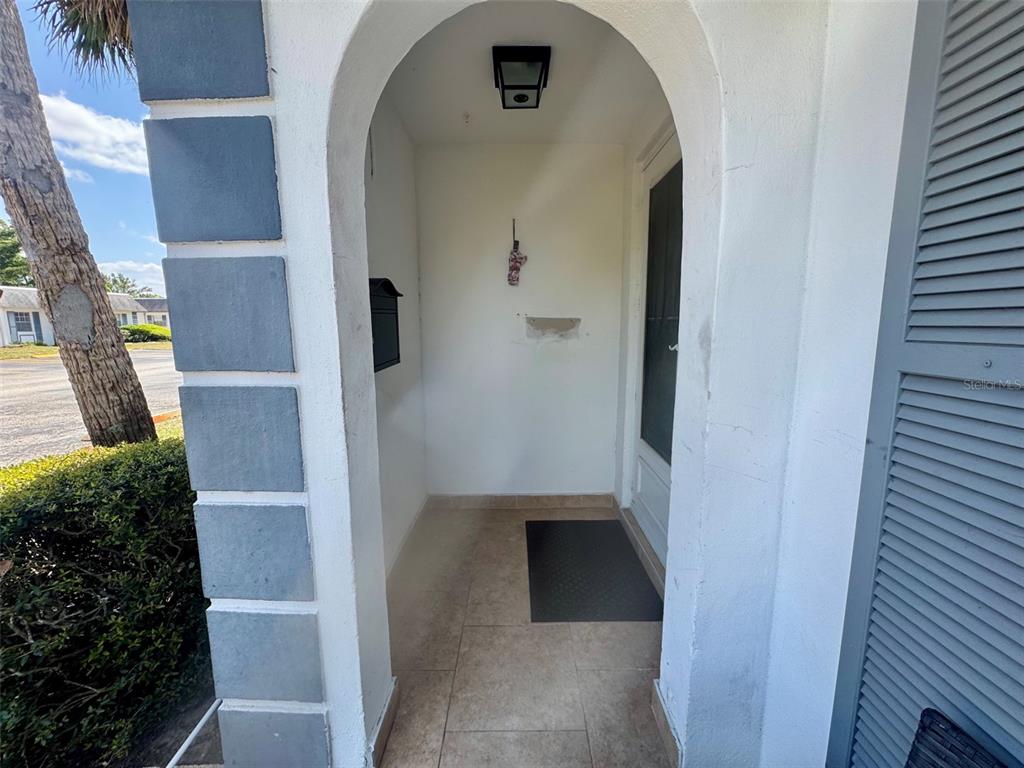 A covered entryway features a tiled floor, a black mailbox, and a white arched entrance — 4235 SHELDON PLACE UNIT 4235, NEW PORT RICHEY, FL