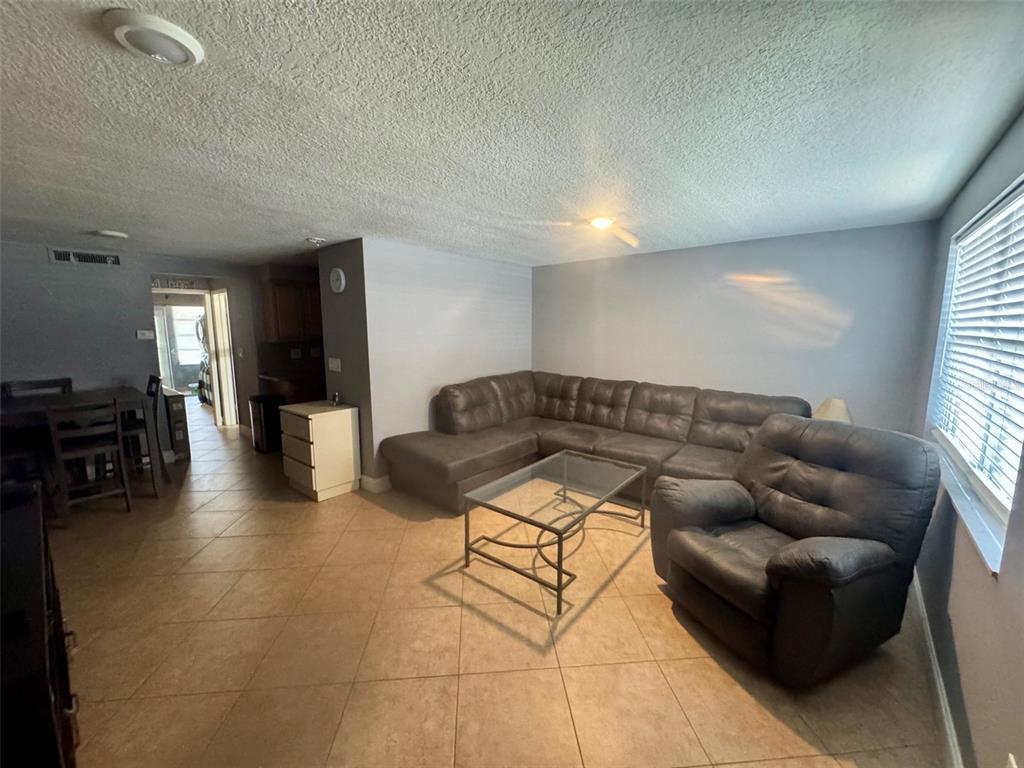 A living room features tile flooring, a large gray sectional sofa, and a glass coffee table — 4235 SHELDON PLACE UNIT 4235, NEW PORT RICHEY, FL