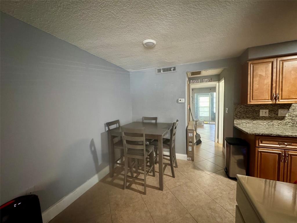 A dining area with a wooden table and chairs sits adjacent to a kitchen — 4235 SHELDON PLACE UNIT 4235, NEW PORT RICHEY, FL