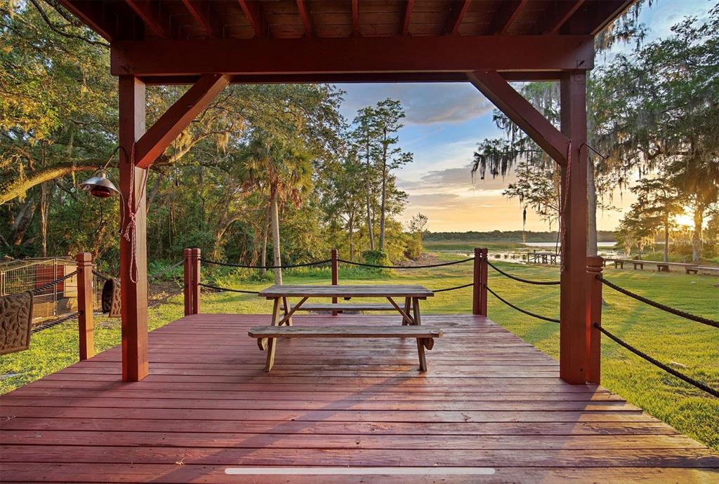 A wooden deck with a picnic table overlooks a grassy yard and a distant lake — 2890 FRONTIER DRIVE, KISSIMMEE, FL