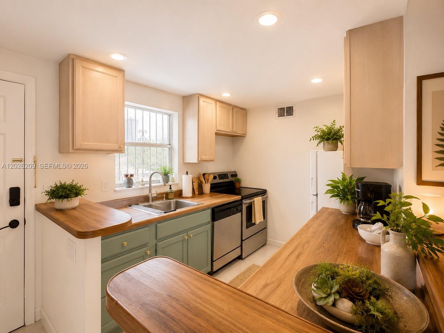 A kitchen features light wood cabinets, green lower cabinets, and wood countertops — 910 Jefferson Ave # 5C, Miami Beach FL 33139, MIAMI BEACH, FL
