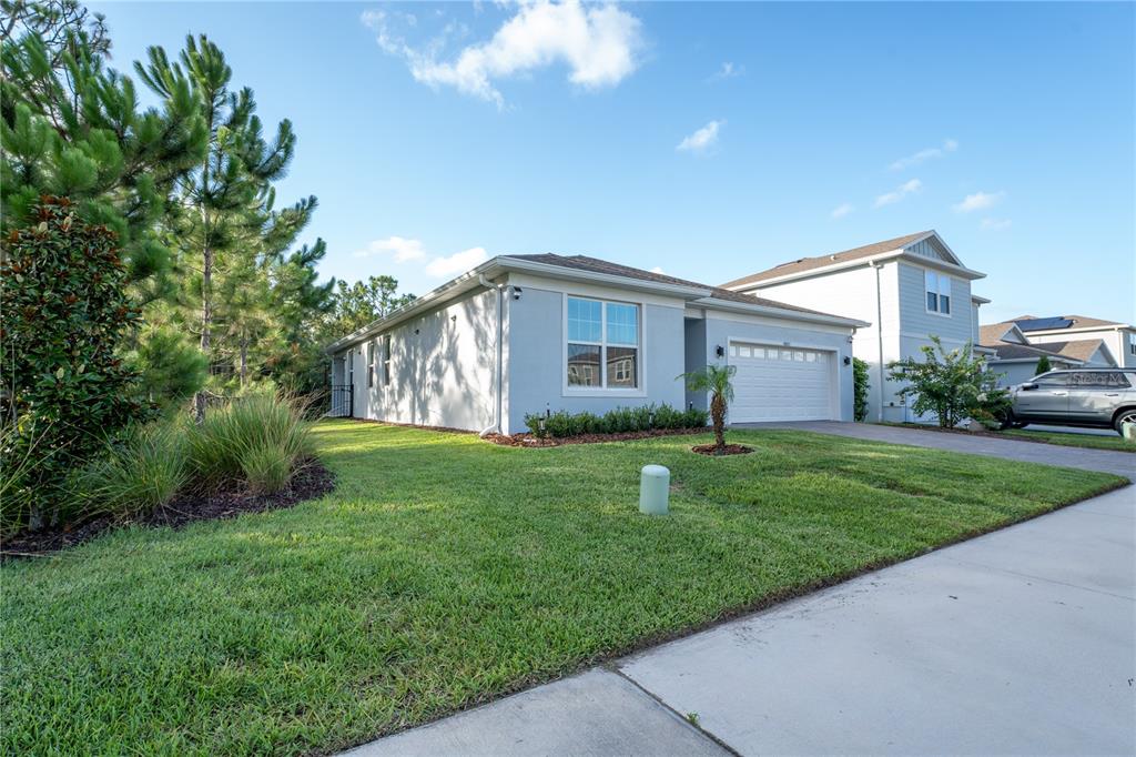 A single-story light blue house with a two-car garage and a landscaped front lawn — 9683 BROWN BURROW STREET, ORLANDO, FL