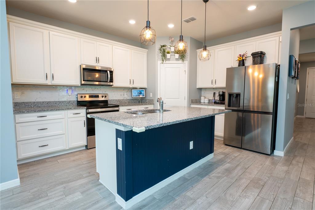A hallway with light wood-look tile flooring, gray walls, and three oval mirrors — 9683 BROWN BURROW STREET, ORLANDO, FL