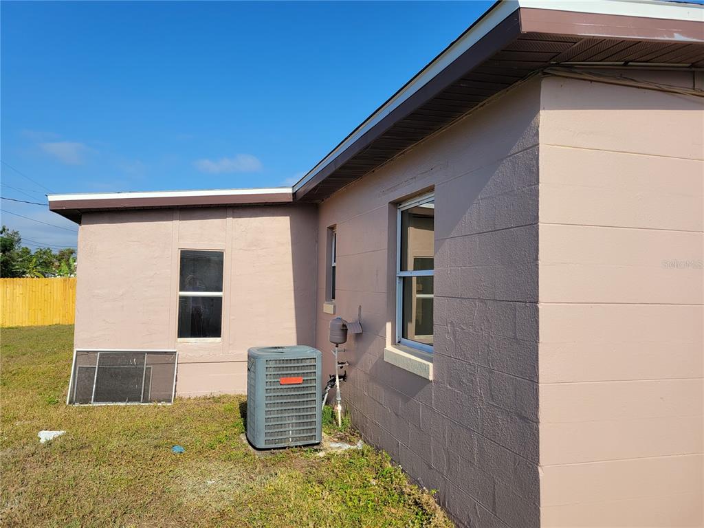The exterior of a tan concrete block house features a window, an air conditioning unit, and a detached screen — 3381 WESTLUND TERRACE, PORT CHARLOTTE, FL