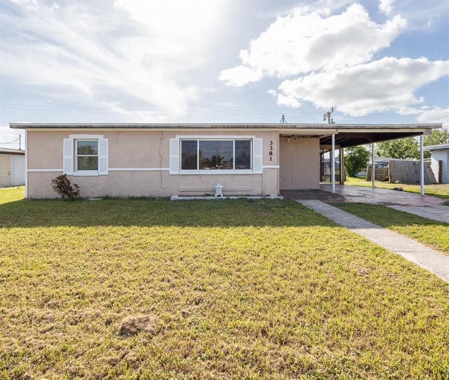 A single-story house with a beige stucco exterior, a carport, and a front lawn — 3381 WESTLUND TERRACE, PORT CHARLOTTE, FL