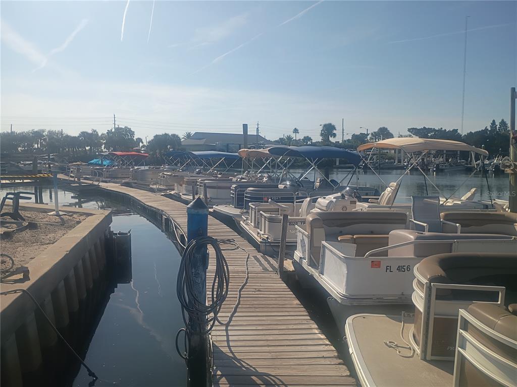 A wooden dock lined with several pontoon boats under blue and tan bimini tops — 147 MIDDLE WAY, NEW SMYRNA BEACH, FL