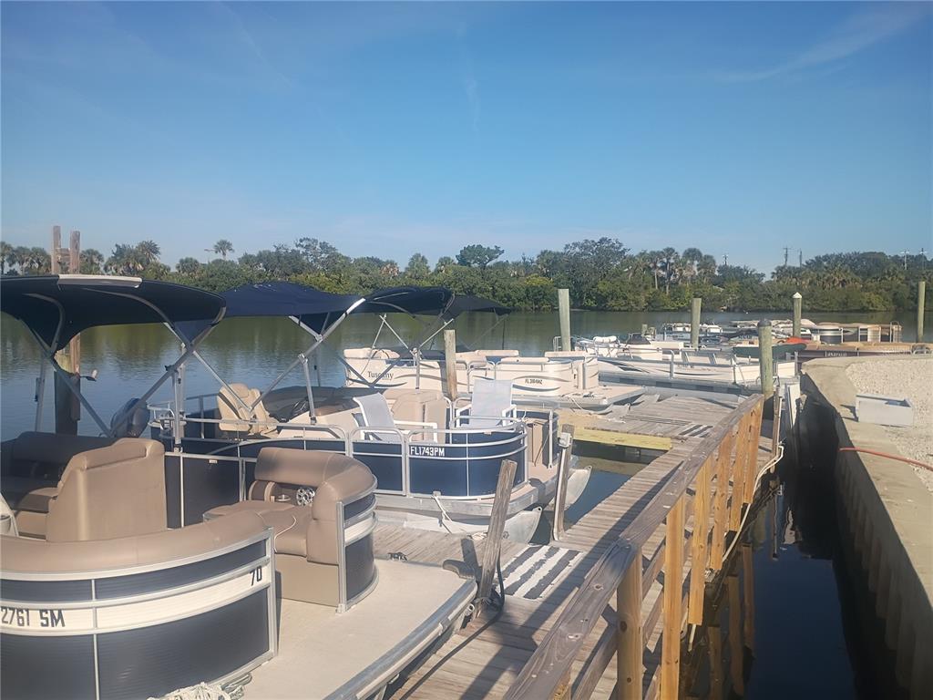Several pontoon boats are docked at a wooden pier along a calm, tree-lined waterway — 147 MIDDLE WAY, NEW SMYRNA BEACH, FL