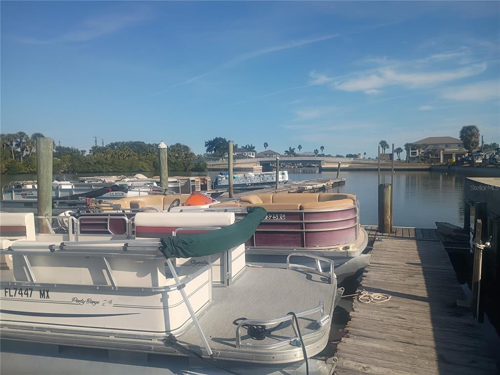 Several pontoon boats are docked at a wooden pier on a sunny day — 147 MIDDLE WAY, NEW SMYRNA BEACH, FL
