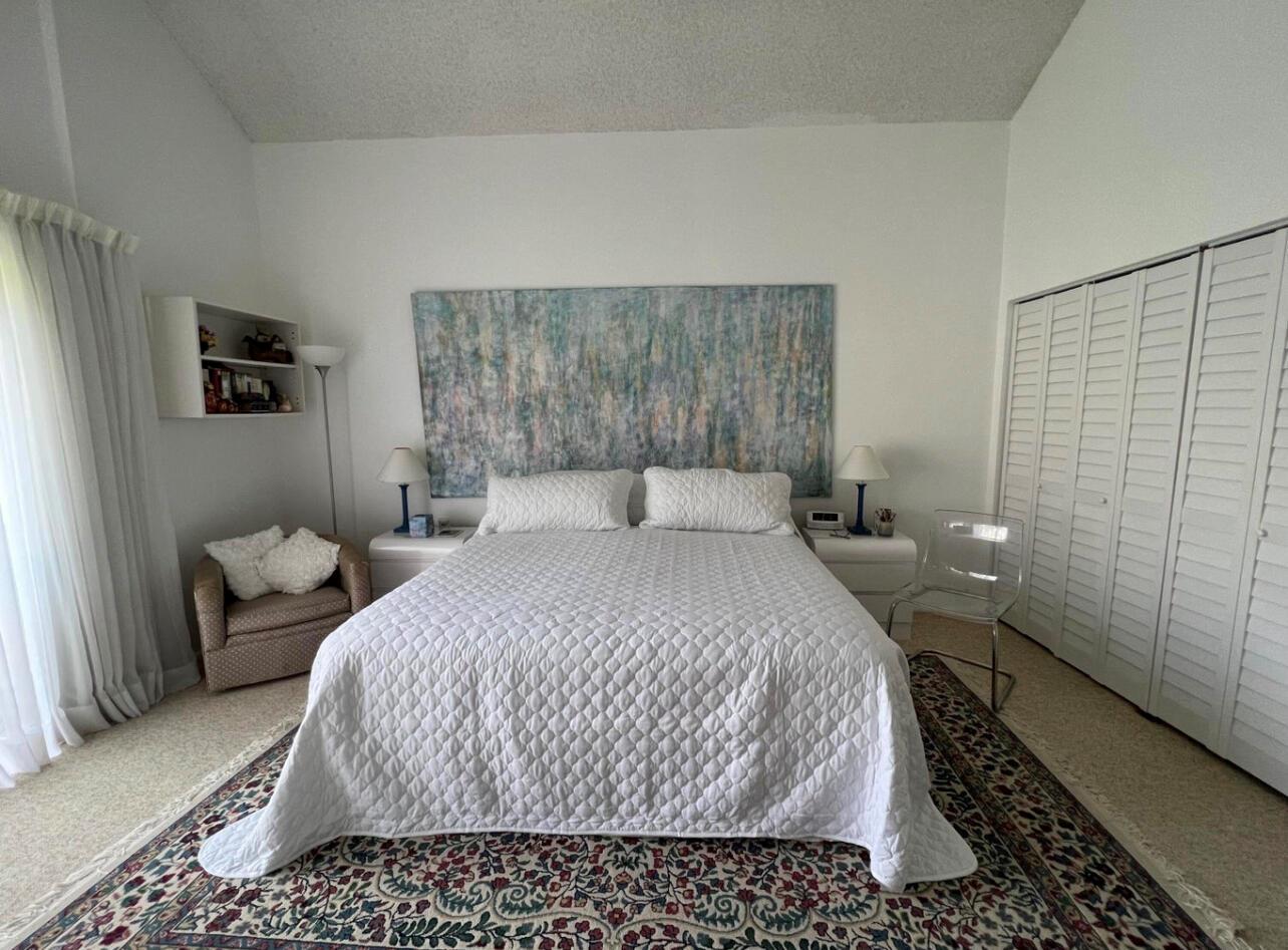 A bedroom features a queen bed, a large abstract painting, and a patterned area rug — 1002 Bridgewood Place # 1002, Boca Raton FL 33434, BOCA RATON, FL